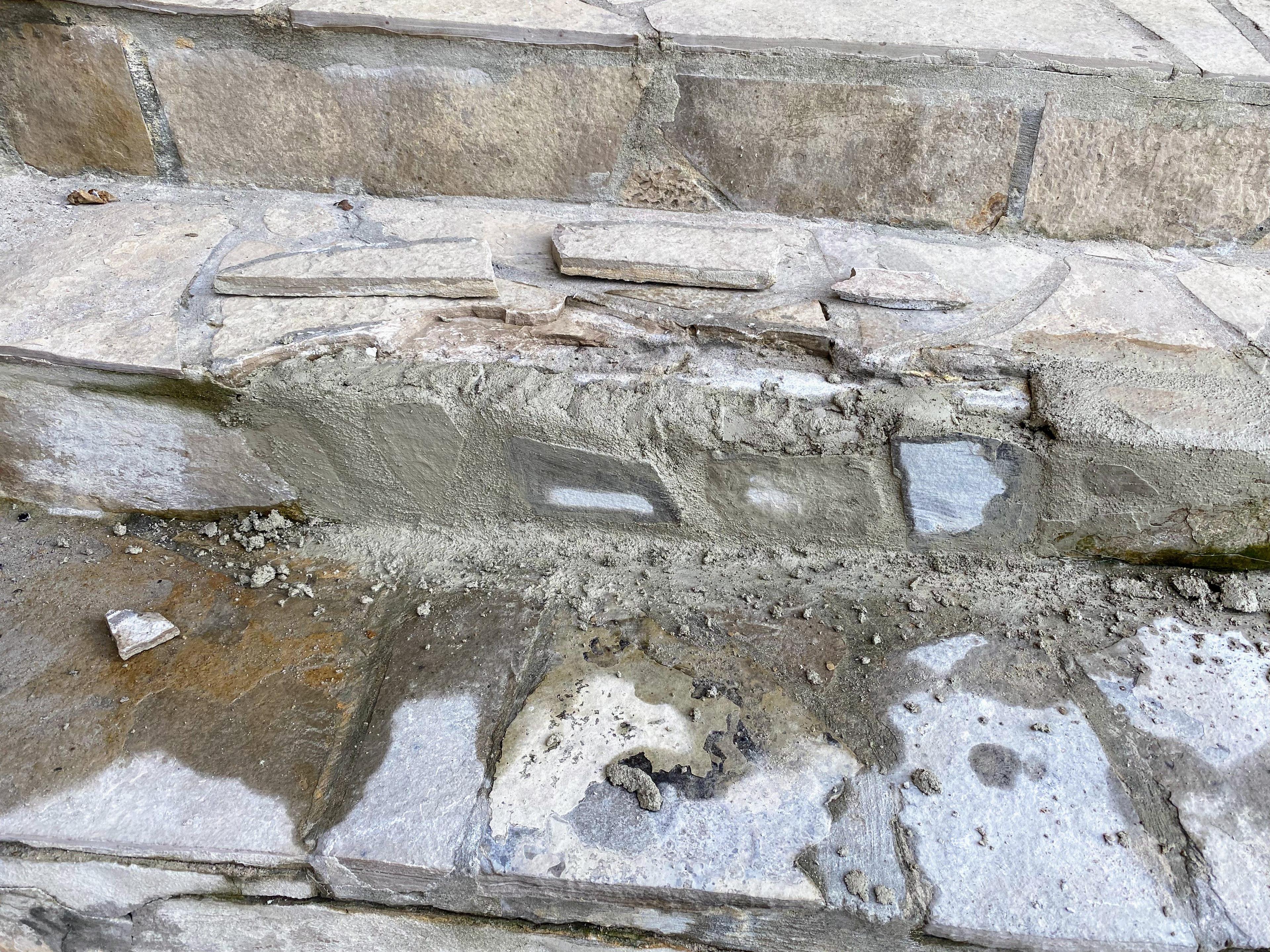 Image of a flagstone stair riser being rebuilt with concrete and stone before the tread is laid.