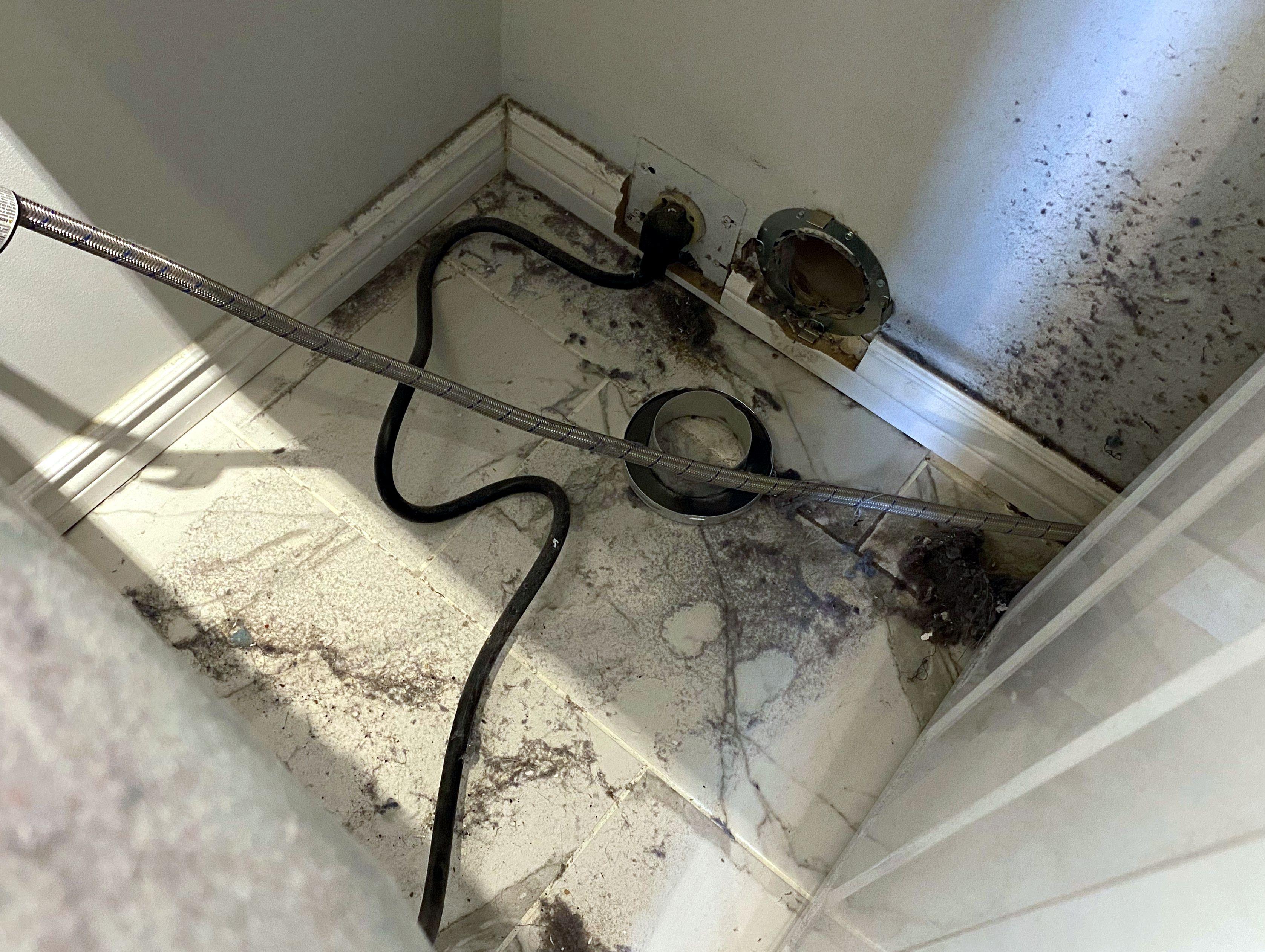 Visible lint leakage below and around dryer and loose vent