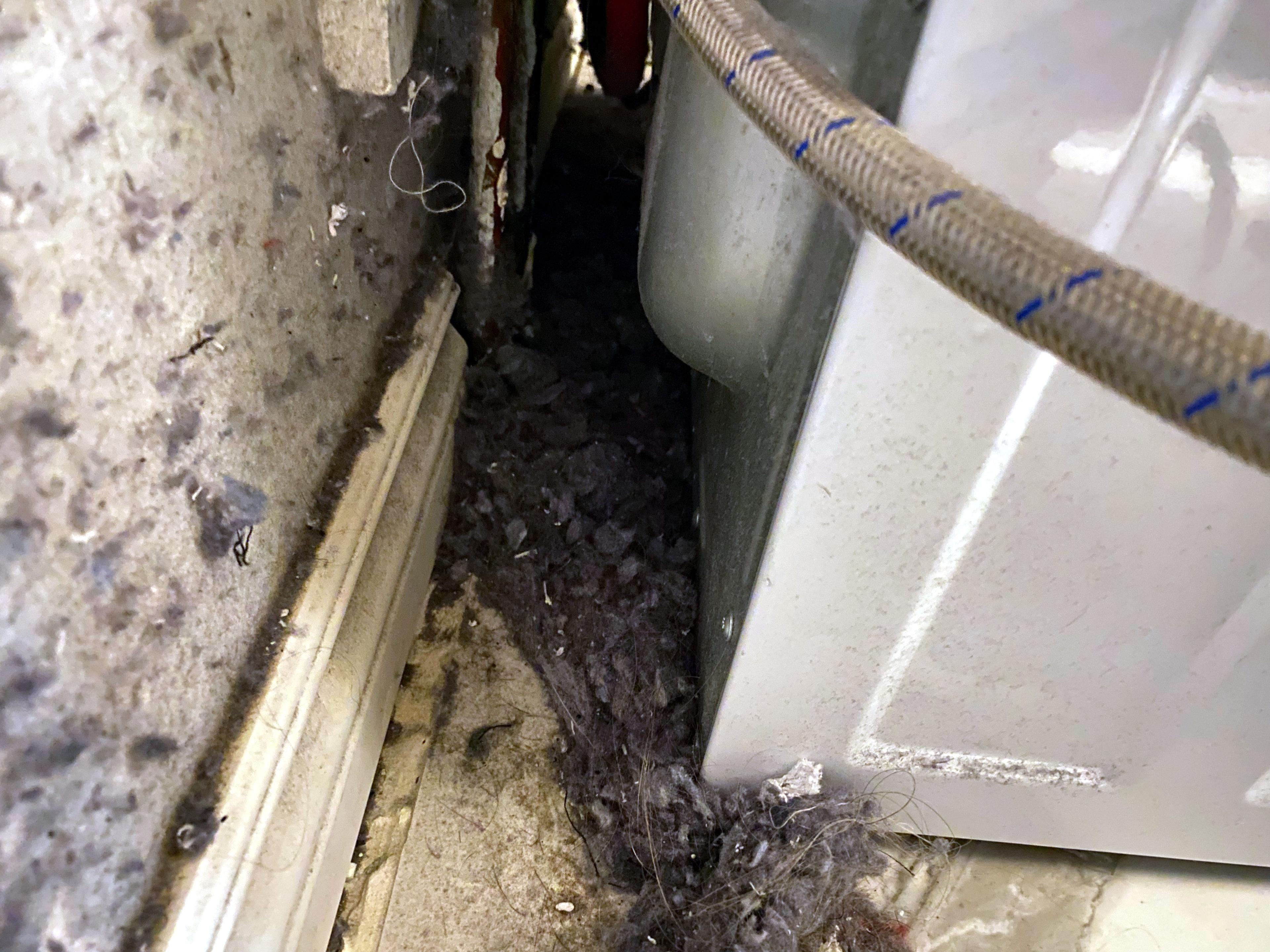 Lint build-up on wall and behind washing machine due to loose dryer vent connection